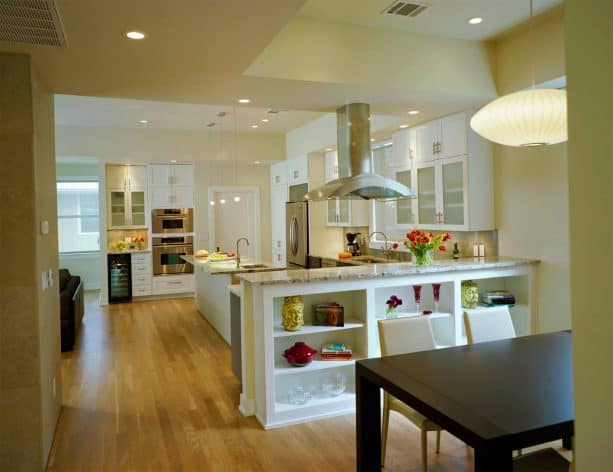 an open kitchen and dining room with a large half wall with built-in shelf