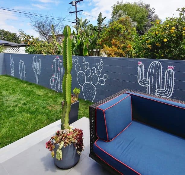 grey painted cinder block barrier walls with white cute cactus murals on it