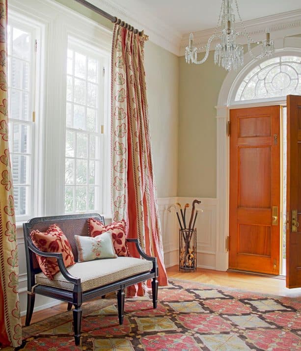 a traditional entry with warm color domination, wood door, and white trim