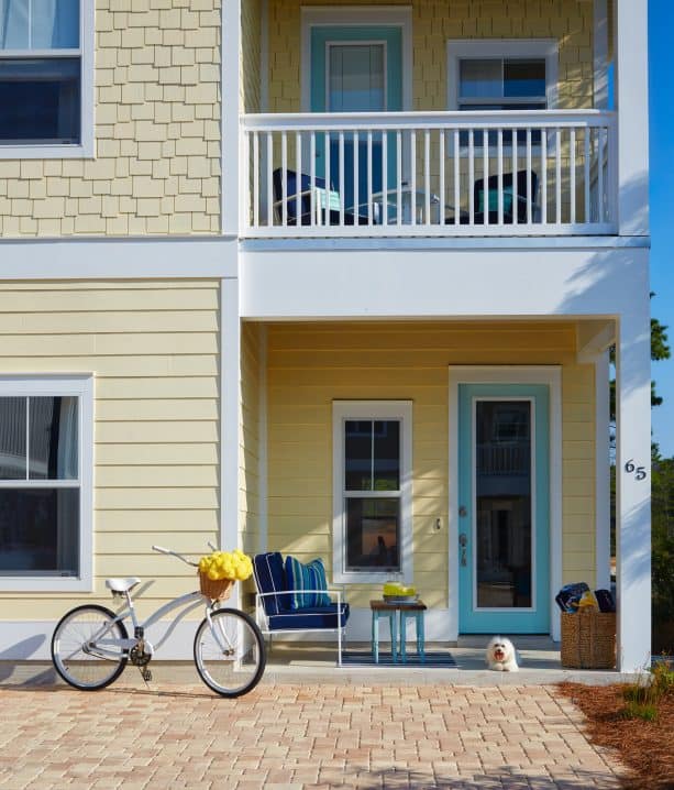 charming exterior with pale yellow, white, and sea glass blue color scheme