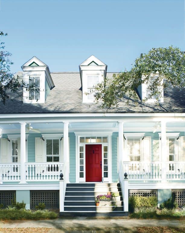 a beach-style house with teal blue wall and blood red door