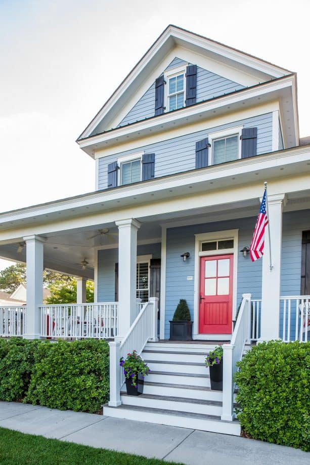 a blue house with a red door and an American flag for a patriotic feel in the home exterior design
