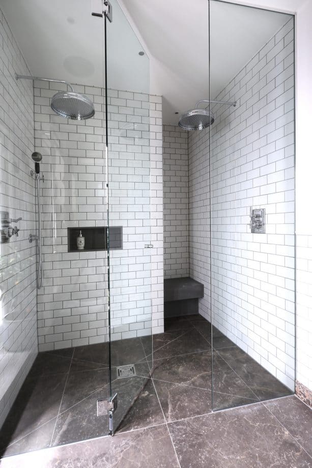 the combination between white subway tile with darker gray grout and natural gray stone flooring