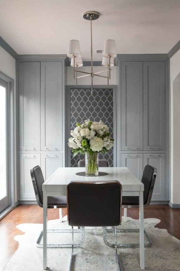 a transitional dining room with white walls, grey trim, and grey custom built-in cabinets