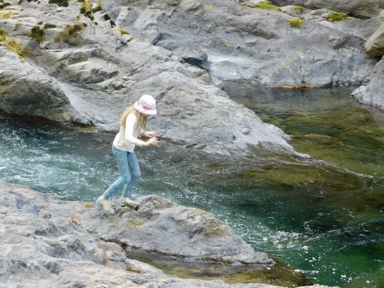A tween enjoys jumping from rock to rock in the clear, rapid sol doc river.