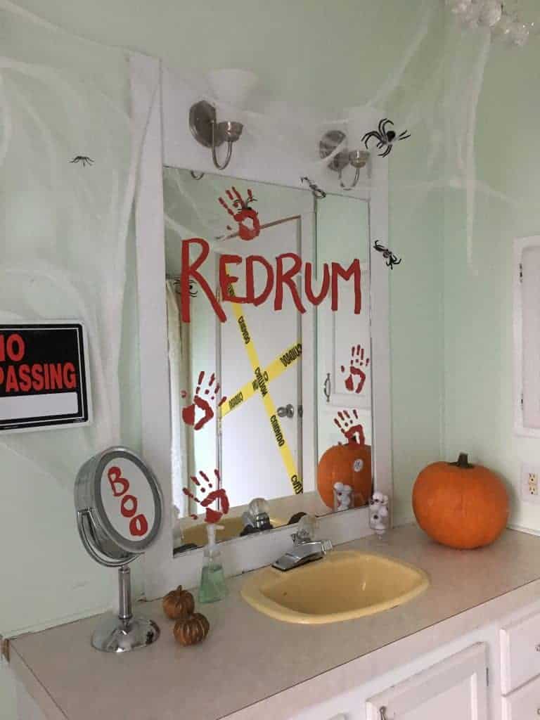 Redrum is painted on a mirror in a halloween themed bathroom