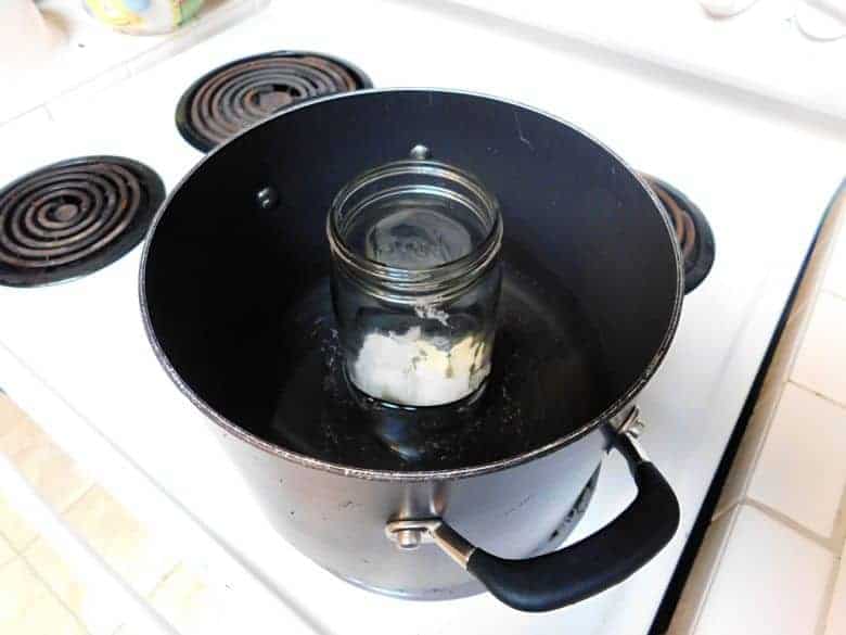 mason jar with melted shea butter in a large pot filled with water