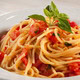Spaghetti ao alho e óleo com pedaços de tomate fresco e folhas de manjericão