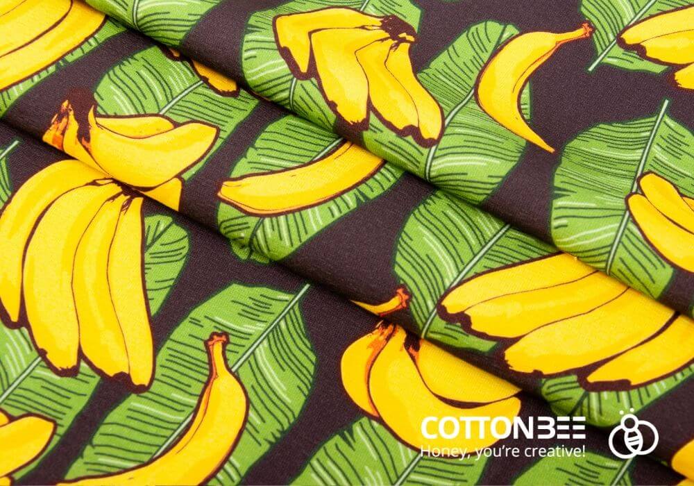 Intensywnie żółte banany z liśćmi bananowca na czarnym tle druk na materiale w liscie bananowca