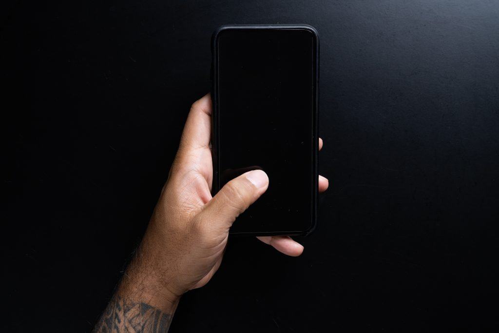customer closing out contactless bar tab on mobile phone blck iphone with mans hand