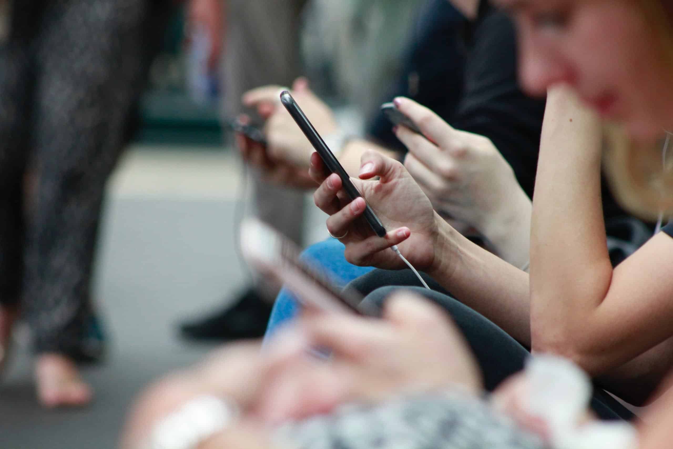 people on mobile phones sitting down