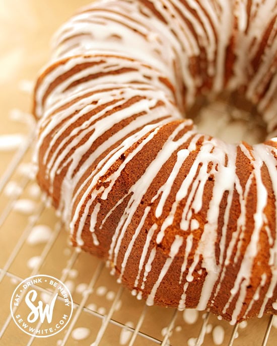drizzling white icing over the bundt cake