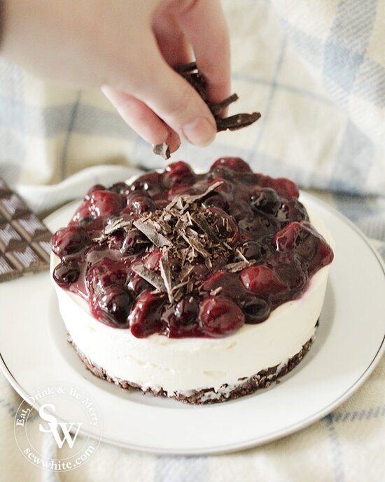 sprinkling chopped chocolate on the Black Forest Cheesecake