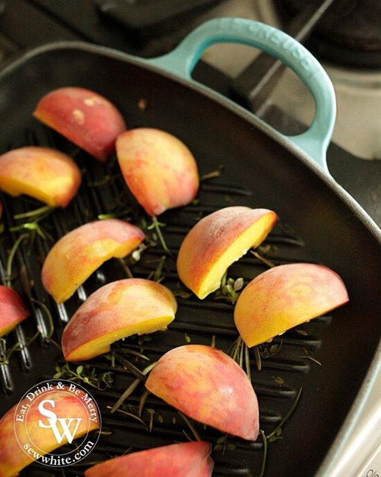 Fresh peaches on a Le Creuset grill pan with fresh thyme and rosemary.