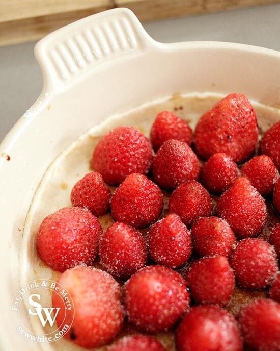 Close up of the strawberries sprinkled in sugar on the bed of puff pastry.