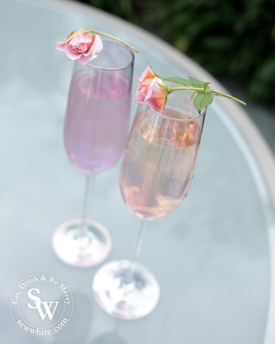 Irredentist purple and pink champagne glasses with roses balanced on top for the Prosecco cocktail