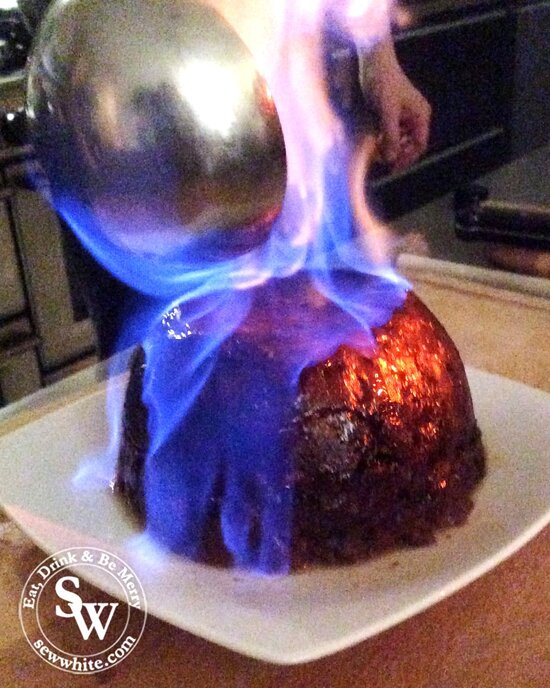 A homemade Traditional Christmas Pudding on fire with blue flame and about to be served.