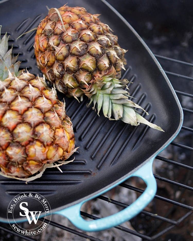 Pineapple being grilled on the campfire on a grill pan.