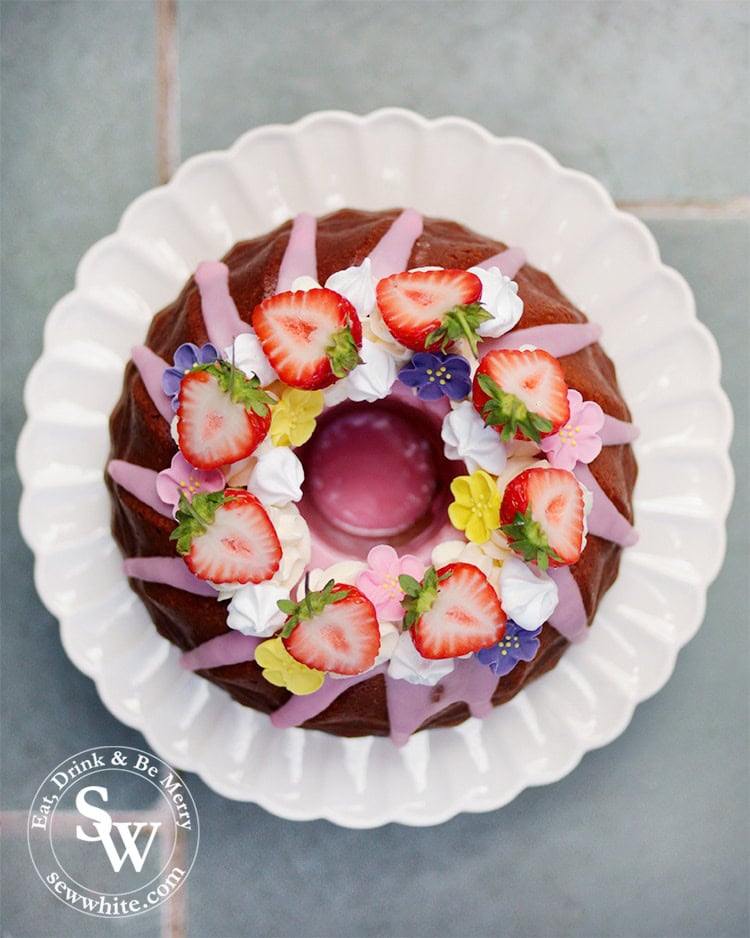 Strawberry Prosecco Cake made with a Le Creuset Kugelhopf tin. Strawberry Prosecco bundt Cake topped with read strawberries, meringues and sugar flowers.
