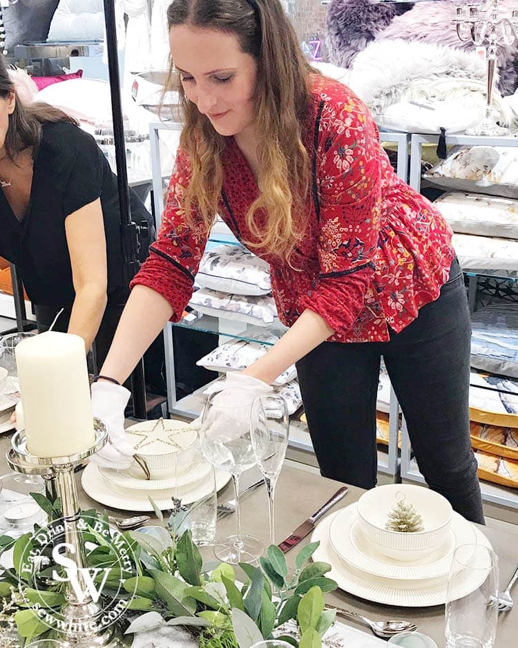 Setting up a Christmas table with silver decorations and beautifully white crockery.