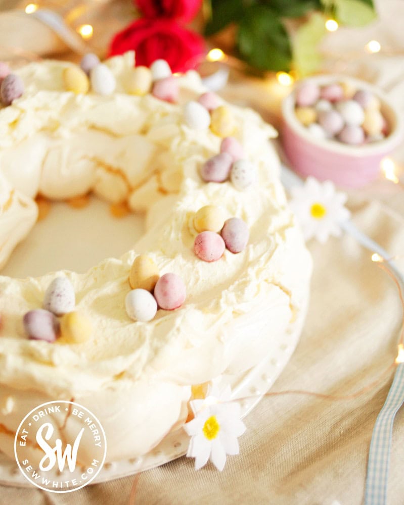 Ready to serve the Easter meringue decorated with fake flowers and mini eggs