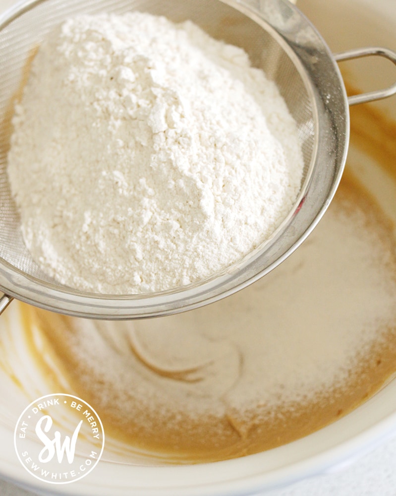 Sieving in the flour into the blondie mix.