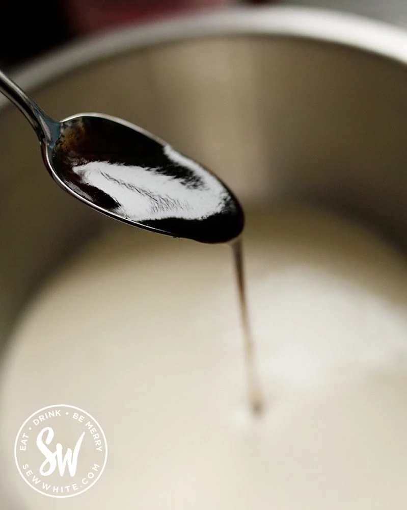 Vanilla paste being spooned into a cream mix