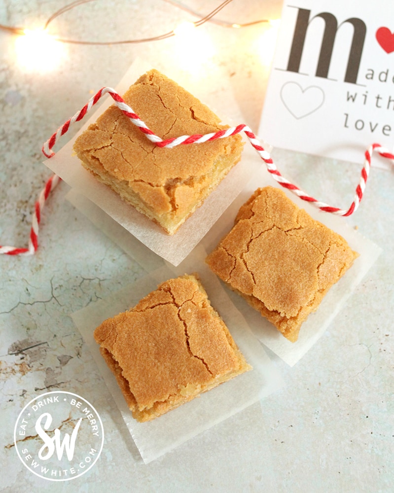 Golden brown easy Blondies sliced up and being wrapped in greaseproof paper and red string