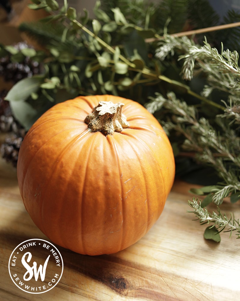 how to cook pumpkin guide - pumpkin on a chopping board with green foliage behind