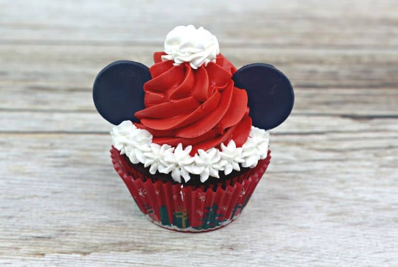 Make this Christmas a Disney Christmas. These adorable Mickey Mouse Santa Cupcakes are the perfect holiday Disney snack to celebrate Christmas. This Disney dessert is so easy and festive. Add a cute Mickey Santa hat to these decorated Christmas cupcakes. #disneysnack #christmascupake #disneyfood