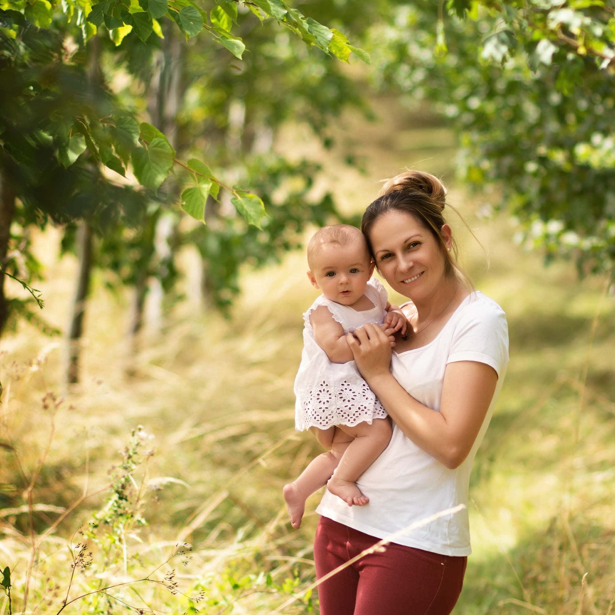 Pamila and daughter Business owner holding her daughter in a field of long grass and trees