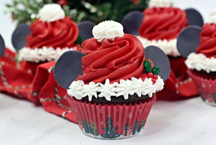 Make this Christmas a Disney Christmas. These adorable Mickey Mouse Santa Cupcakes are the perfect holiday Disney snack to celebrate Christmas. This Disney dessert is so easy and festive. Add a cute Mickey Santa hat to these decorated Christmas cupcakes. #disneysnack #christmascupake #disneyfood