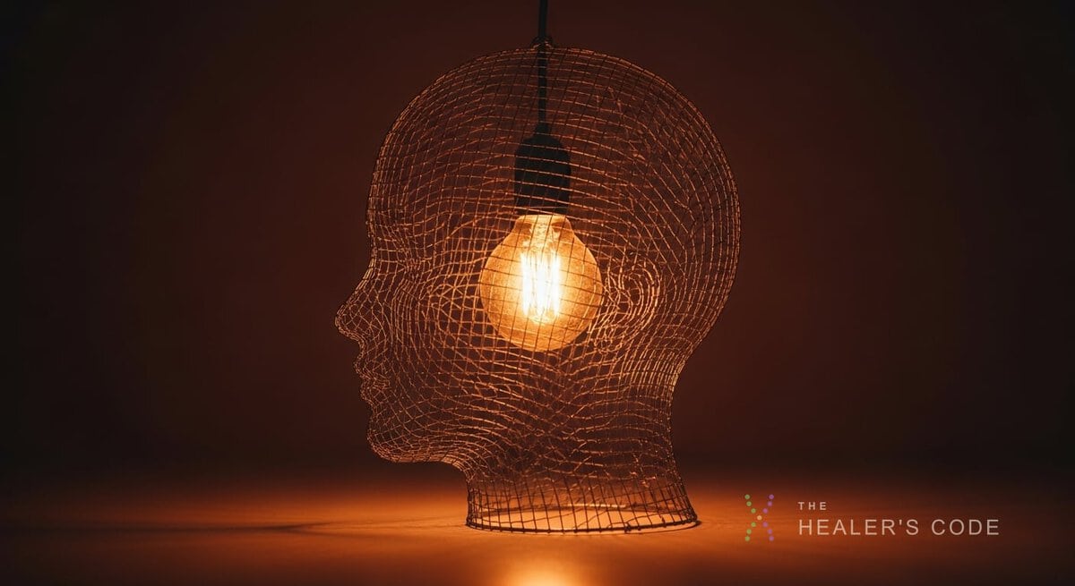 A glowing light held inside a wire-mesh outline of a human head against a dark background