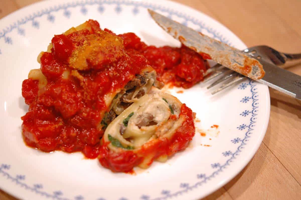 Baked Spinach and mushroom lasagna rolls on a plate sliced open