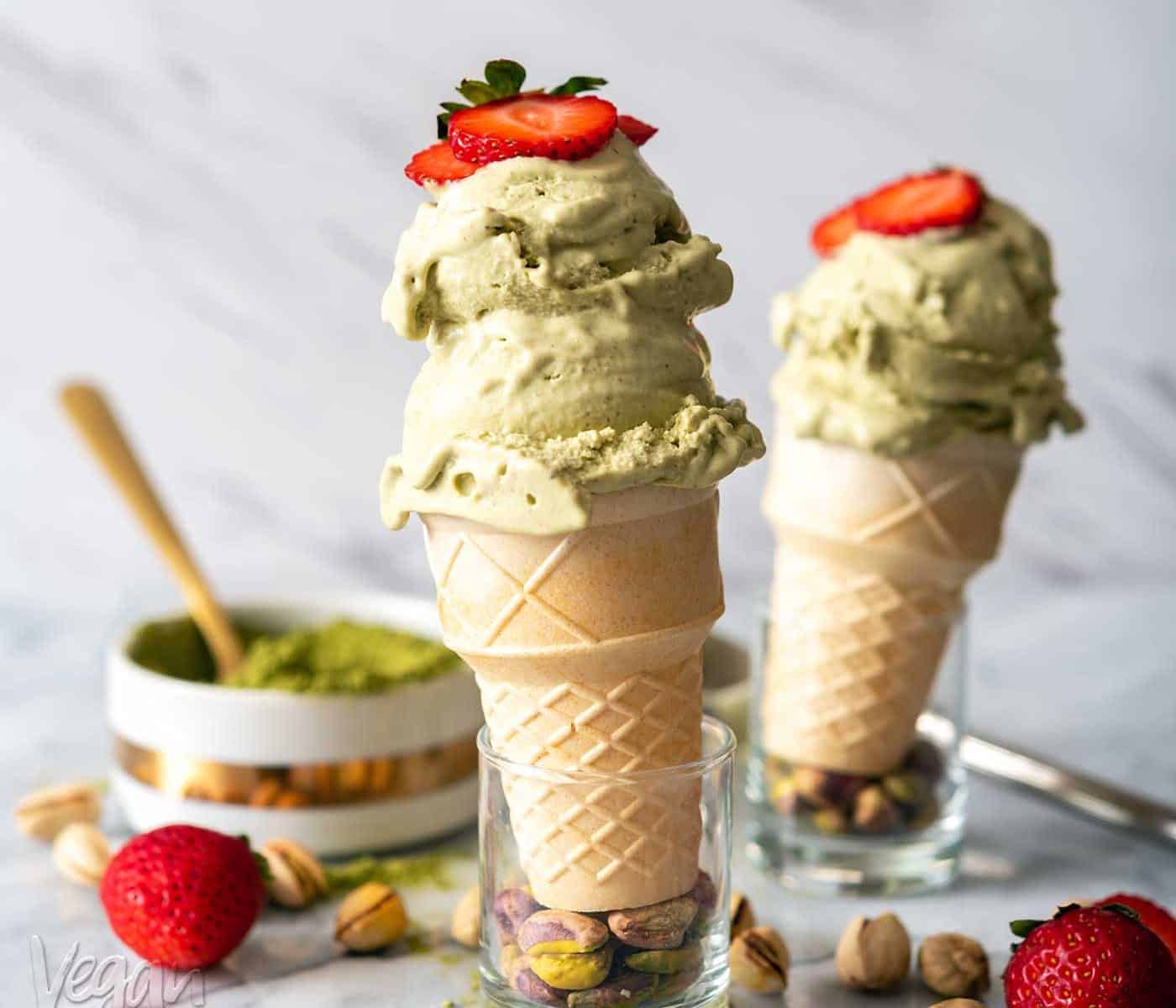 Image of two cones of pistachio matcha ice cream on a marble counter top