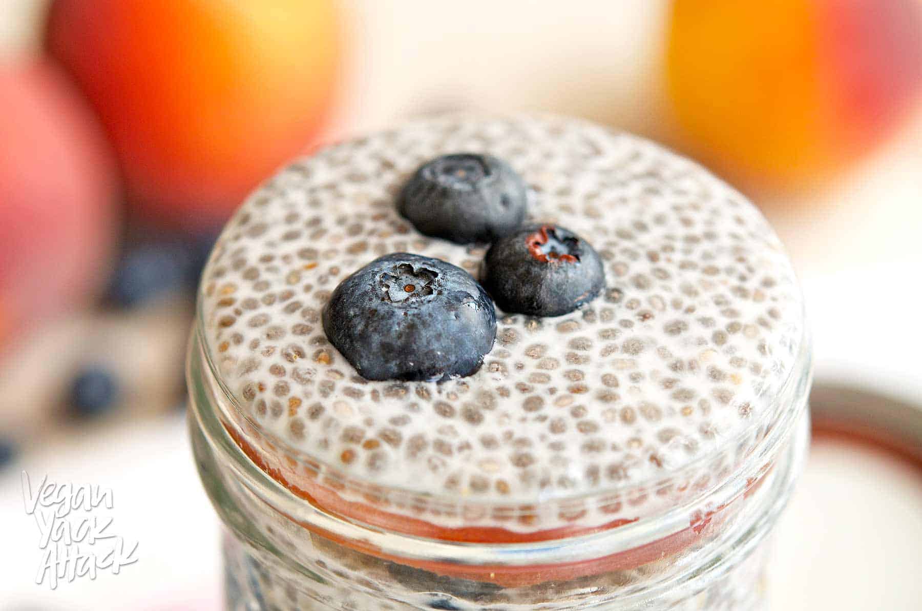 Blueberry peach chia parfait in a glass jar on a floral linen