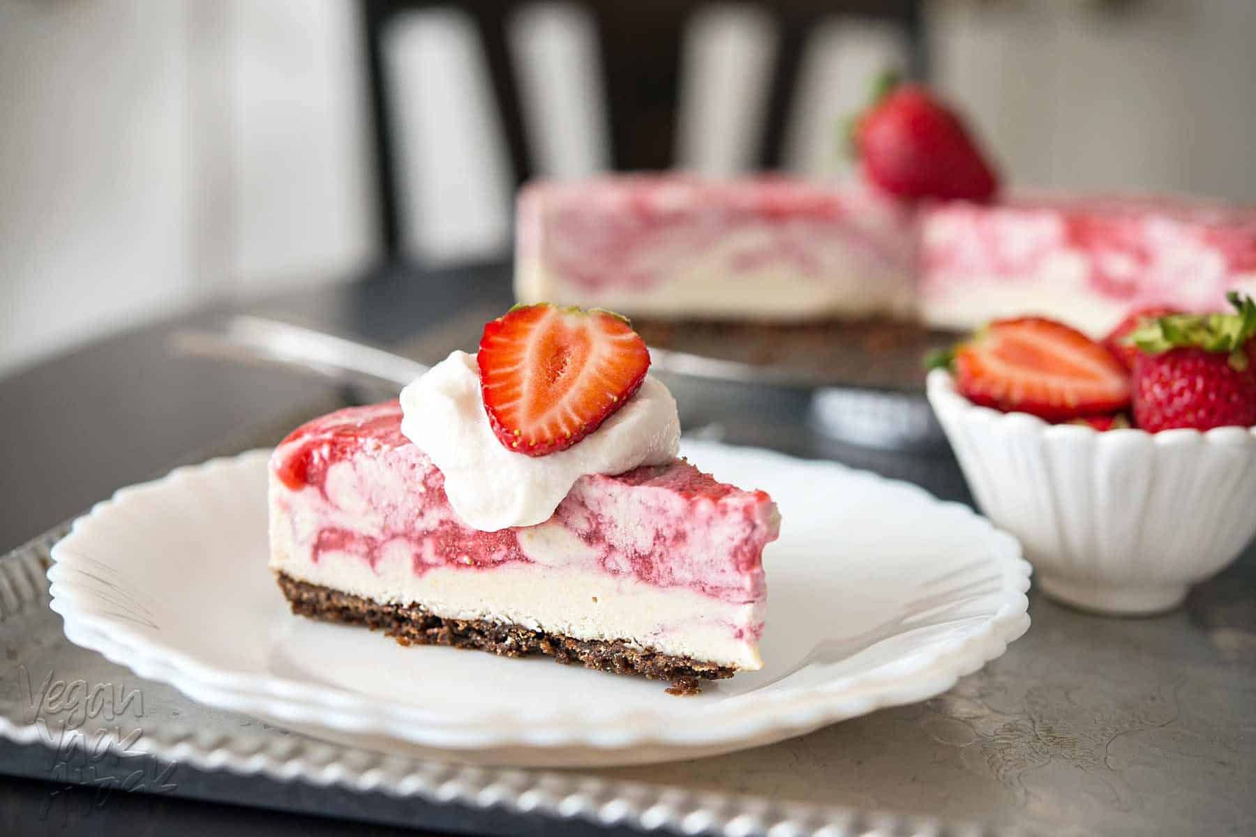 Slice of strawberry swirl cheesecake on a white plate