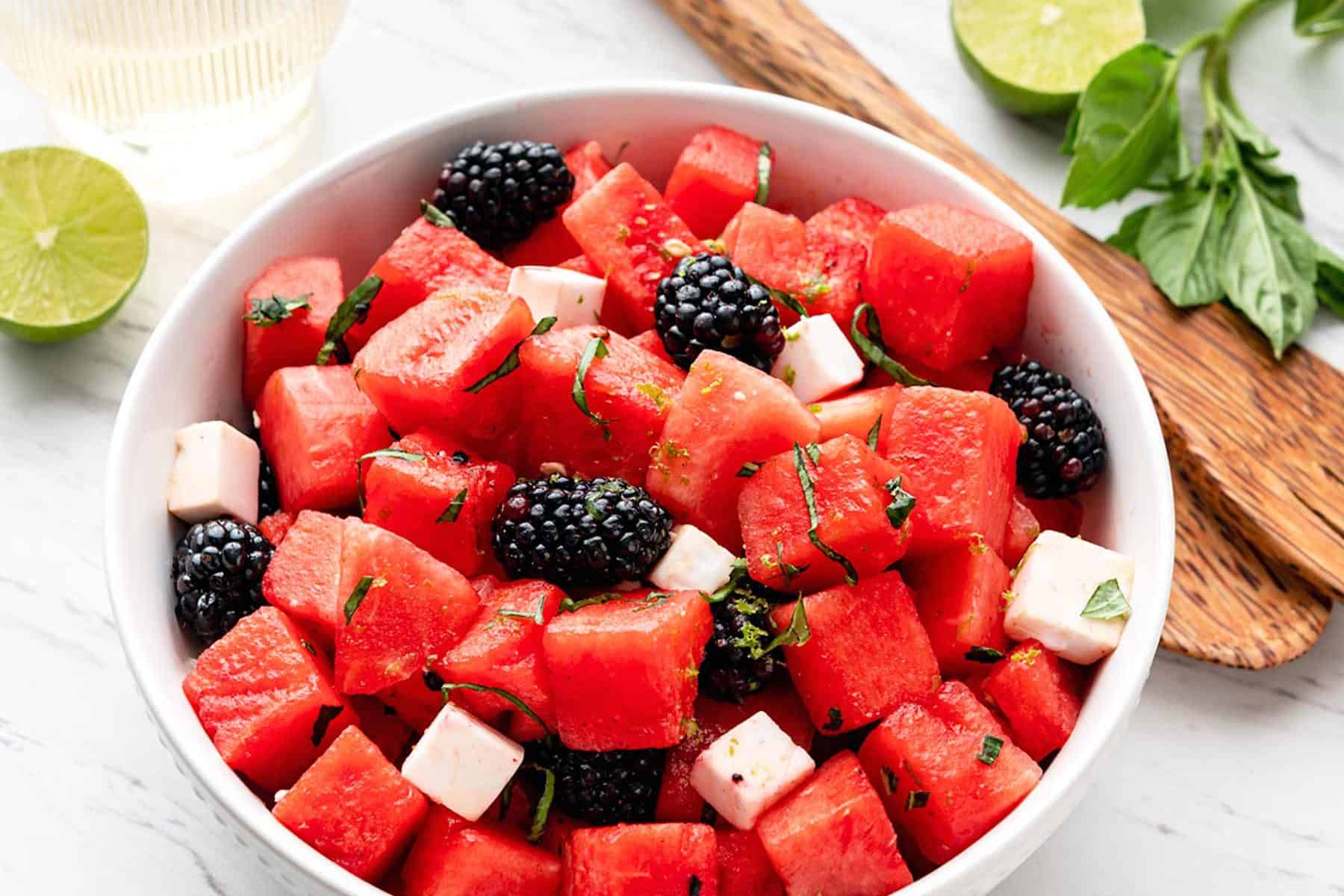 Watermelon Blackberry Feta Salad in a large white bowl with wooden tongs