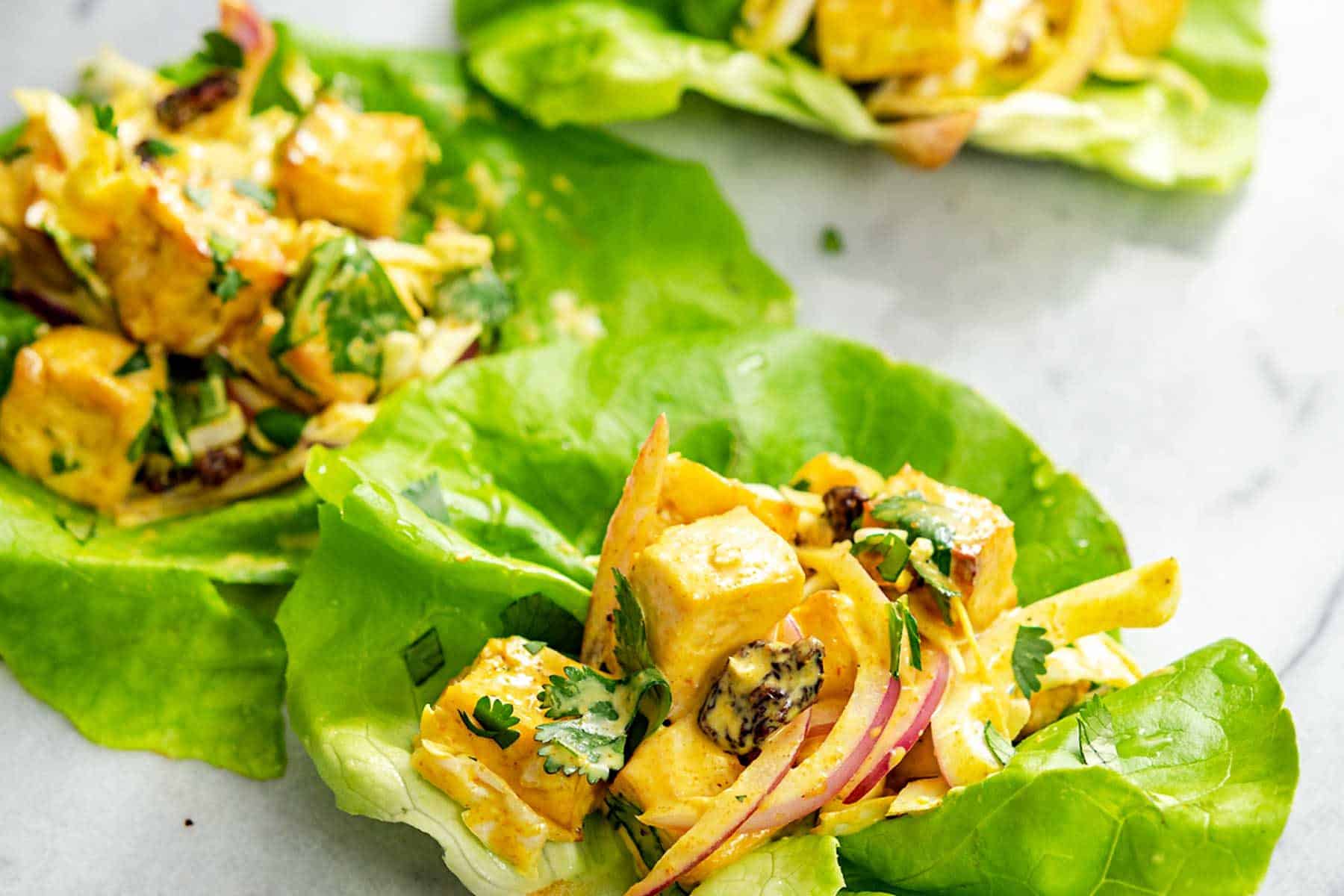 several curried tofu lettuce cups on a marble surface