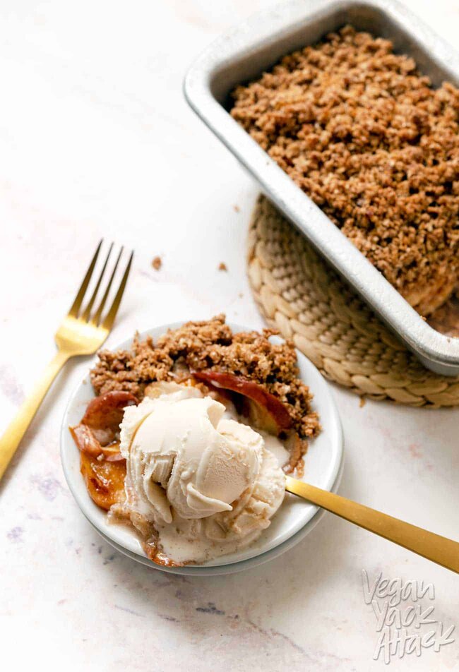 Vegan Apple Pear Crisp A small plate with a scoop of ice cream and scoop of apple pear crisp with gold forks