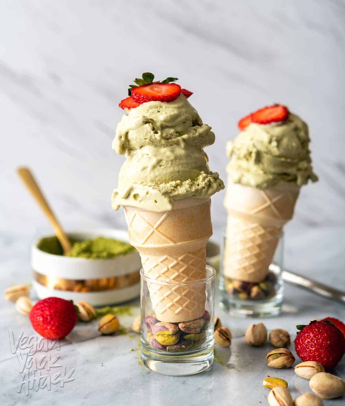 Image of two cones of pistachio matcha ice cream on a marble counter top