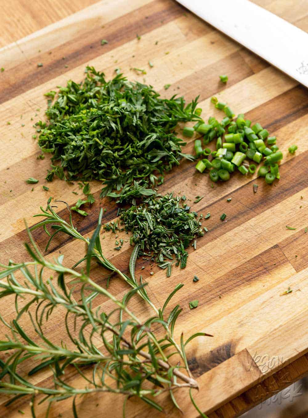 Image of chopped herbs and carrot greens on a cutting board