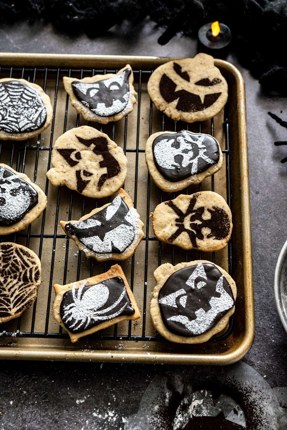 Baking sheet and cooling tray with halloween-stenciled shortbread cookies on it