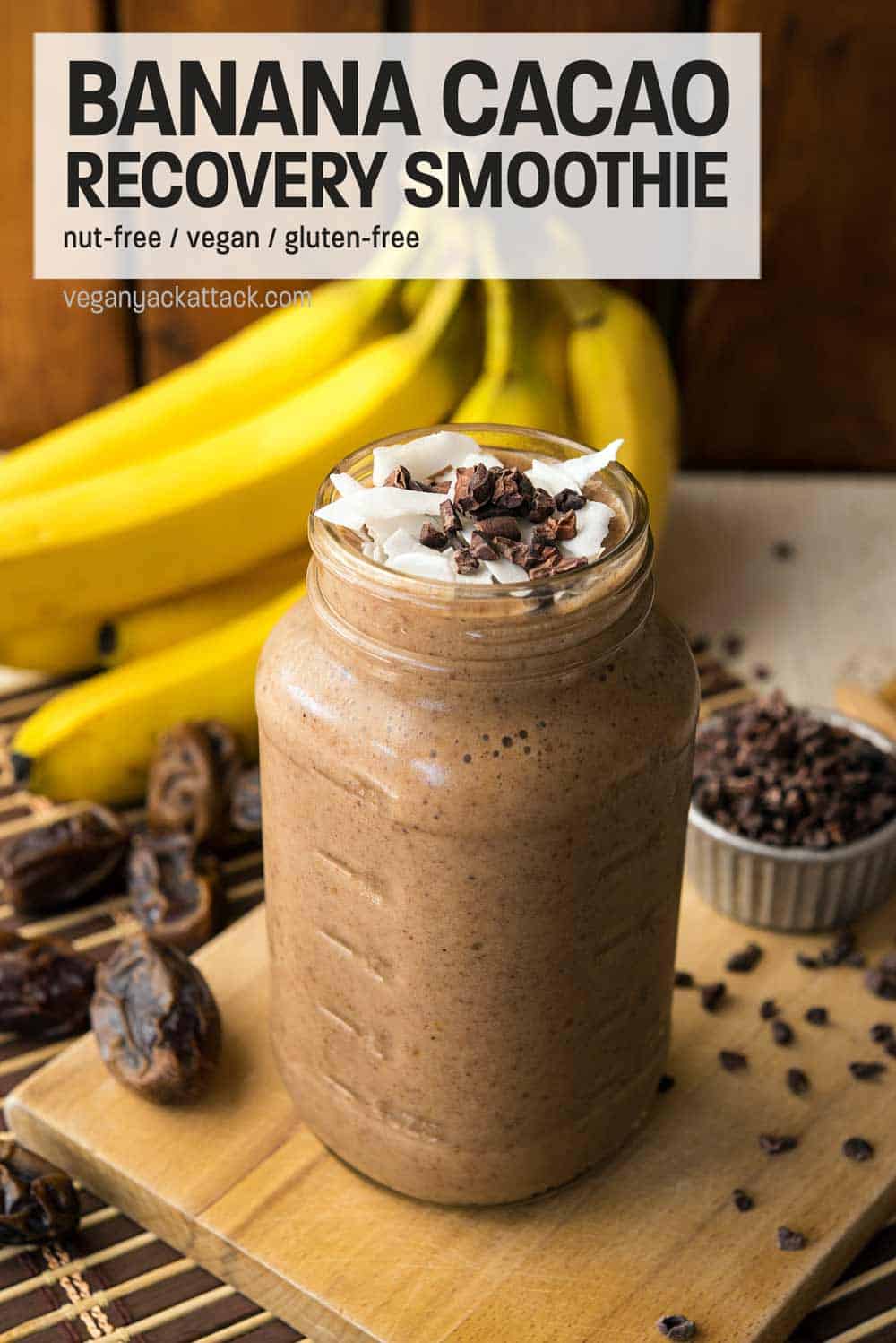 Large jar filled with banana cacao recovery smoothie, on a bread board surrounded by ingredients