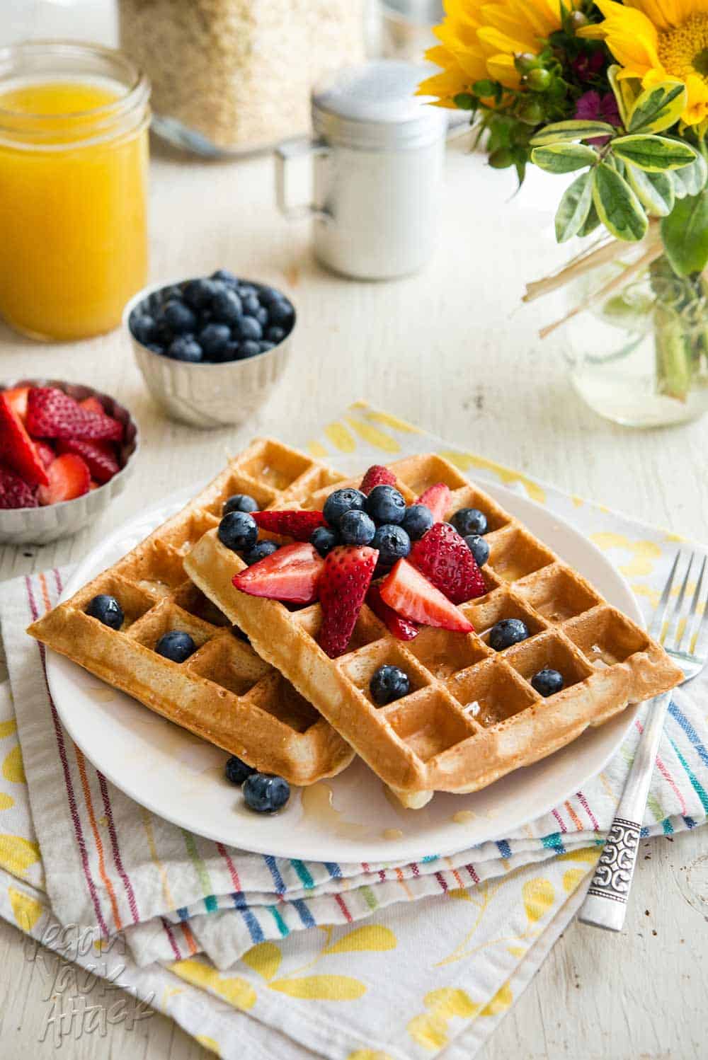 Berry Pineapple Belgian Waffles two berry pineapple belgian waffles on a white plate, topped with berries, sitting atop two colorful napkins