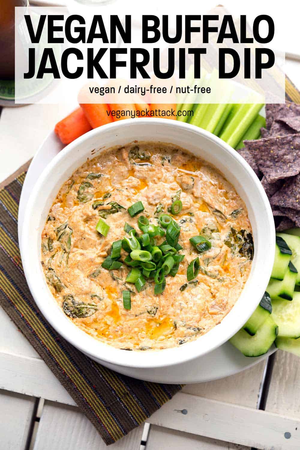 Vegan Buffalo Jackfruit Dip in a white serving dish surround by chips and veggie dippers