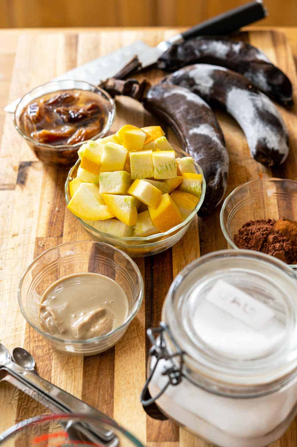 Squash, tahini, cocoa powder, salt, banana, dates, and salt on a cutting board