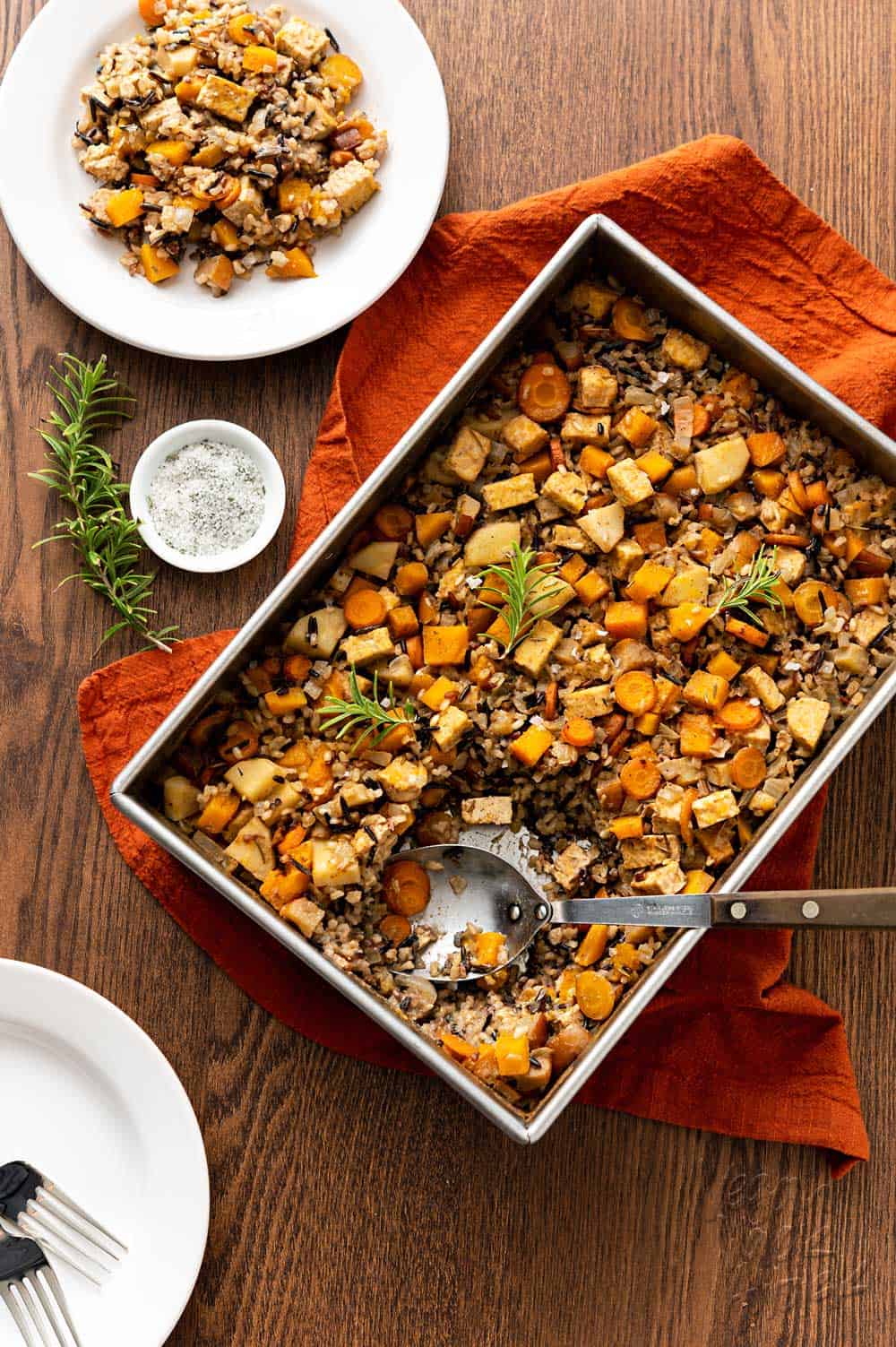 Large baking pan of squash wild rice bake on a brown wood table with rust-colored linen