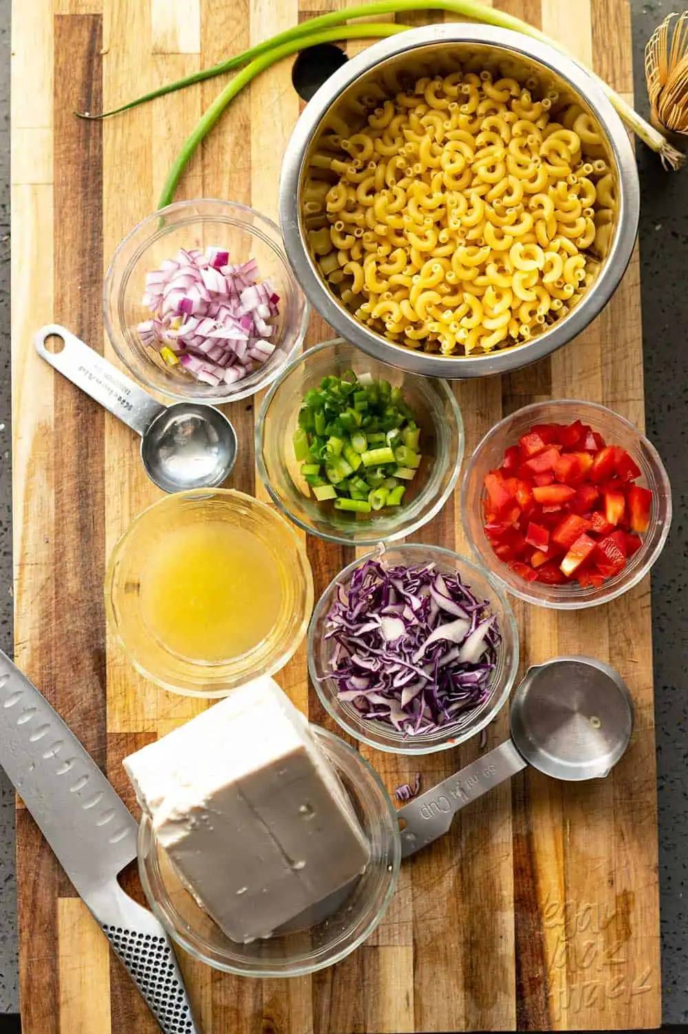 Small bowls with pasta, onions, cabbage, lemon juice and more on a cutting board