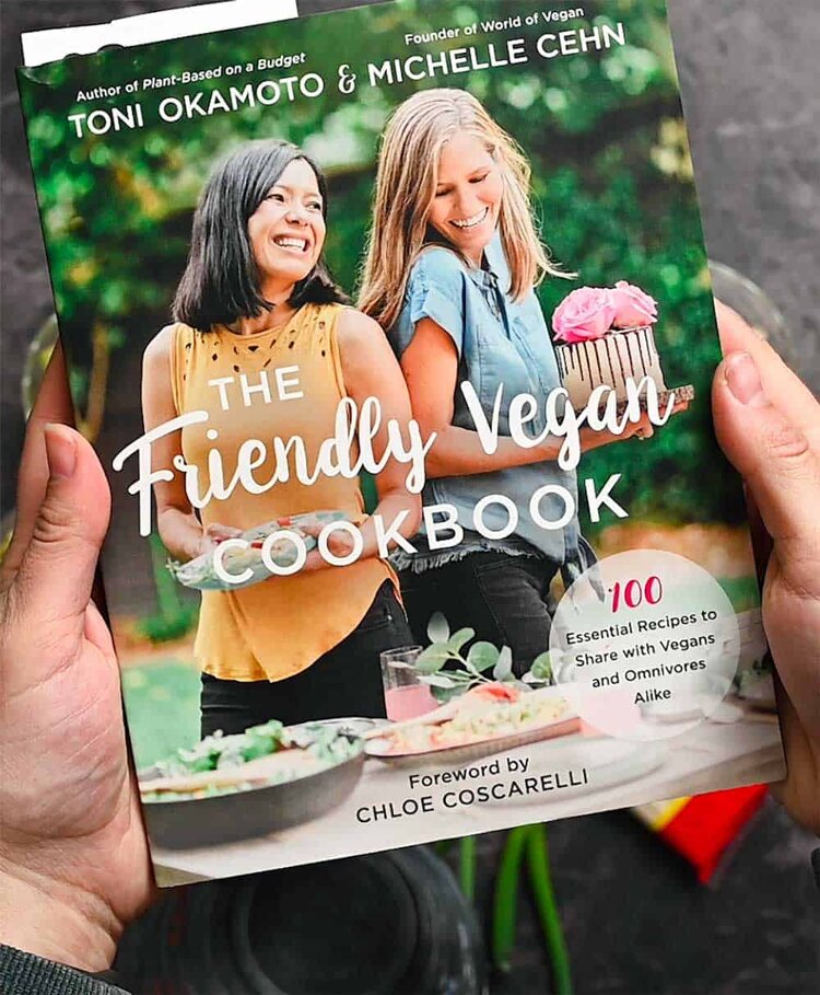 Hands holding The Friendly Vegan Cookbook